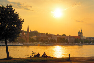 Sunset on the river in the city. Sitting relaxing people with bicycle