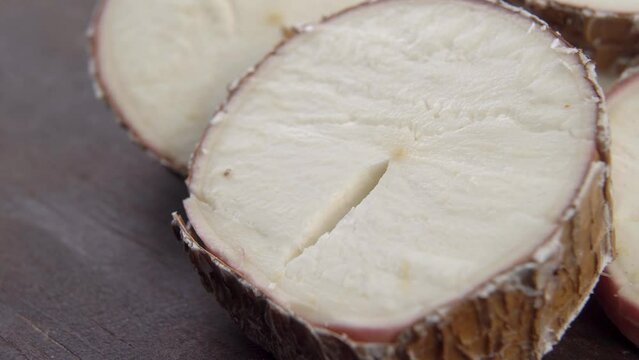 Sliced yucca root. Raw manioc slices on wooden brown surface. Dried cassava plant. Macro. Rotation