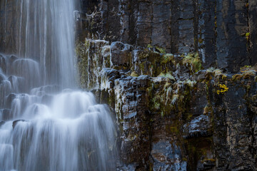 Long exposure of waterfall over basaltic rocks with ice