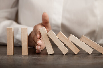 hand stops falling wooden domino blocks, risk insurance concept, crisis manager, domino principle