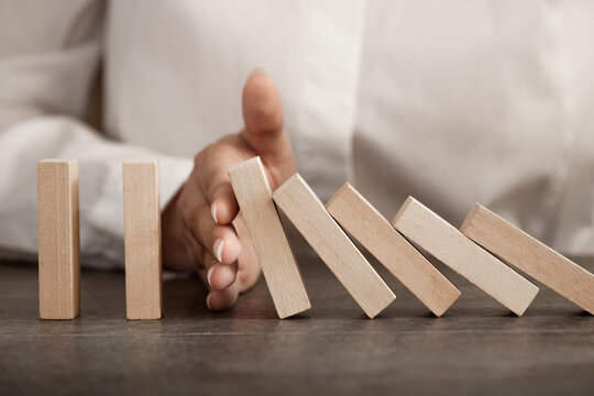 hand stops falling wooden domino blocks, risk insurance concept, crisis manager, domino principle