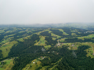 Obraz premium Green slopes of Ukrainian Carpathian mountains in summer. Cloudy morning, low clouds. Aerial drone view.