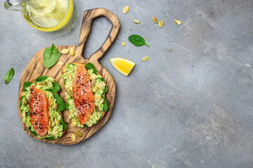 Delicious breakfast or snack sandwich salmon, avocado, spinach, nuts, sunflower seeds, toast with red fish and guacamole. Healthy, clean eating. Vegan or gluten free diet. top view, copy space
