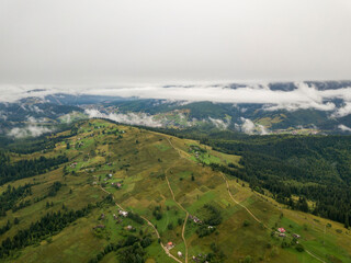 Obraz premium Green slopes of Ukrainian Carpathian mountains in summer. Cloudy morning, low clouds. Aerial drone view.