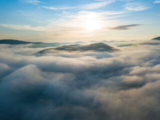 Obraz premium The rays of dawn over the fog in the Ukrainian Carpathians. Aerial drone view.