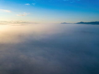 Fototapeta premium The rays of dawn over the fog in the Ukrainian Carpathians. Aerial drone view.