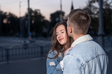 Fototapeta premium Young beautiful couple in love hugs on evening city background