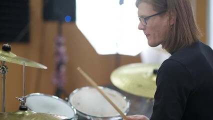 Young adult men and women learn to play drums at school. Hobbies and pastime. Art and life style.