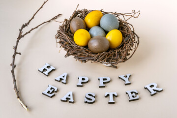 Happy easter lettering, branch and colorful Easter eggs in birds nest on gray background