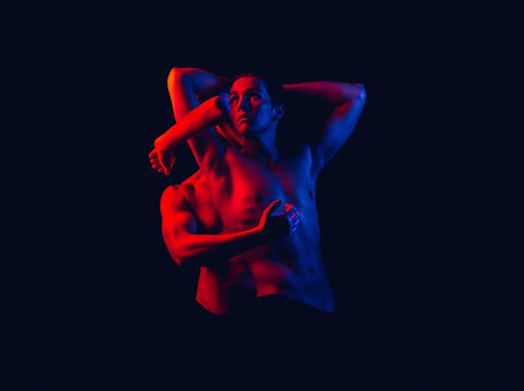 Fashion art photo of strong young sportsman in red and blue neon colors on isolated dark background. Sexy naked torso.