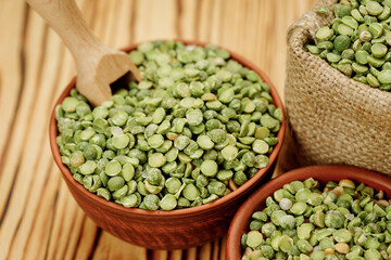 Green pea groats in bowls and bags on a wooden background. High quality photo
