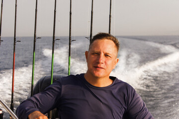 A 45-46-year-old man is traveling at speed across the sea on a high-speed boat. The wind blows in his face. The concept of freedom.