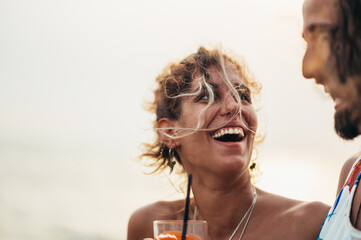 Attractive young couple with alcohol cocktails having fun on the beach