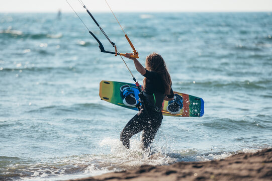 Woman holding kiteboard and going into the water
