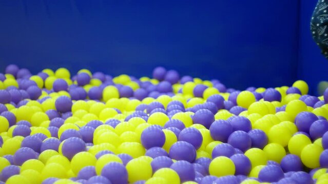 A cheerful Caucasian boy 7 years old jumps and bathes in colored balls in a children's entertainment center. A game center for children. Children's vacation, fun entertainment