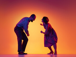 Portrait of excited man and woman, couple of dancers in vintage retro style outfits dancing lindy hop dance isolated on gradient yellow and purple background.