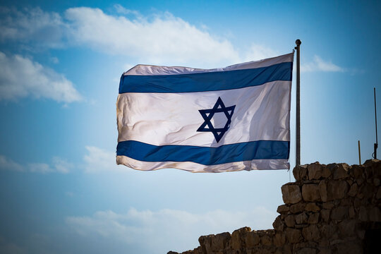 Flag of Israel fluttering in strong wing against cloudy sky