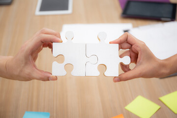 Hands of team young business and partner holding piece jigsaw for assembly is metaphor, teamwork...