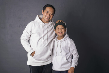 Father and son smiling and standing together wearing white hoodie for apparel mock up, isolated on...