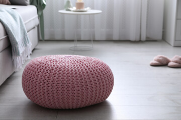 Pink knitted pouf near sofa in living room. Space for text