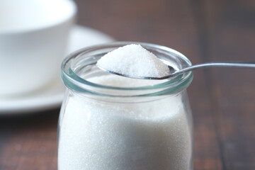 white sugar and spoon in a container on black background,