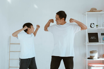 Asian young father and son in white tshirt are playing together at home showing cheerful and...