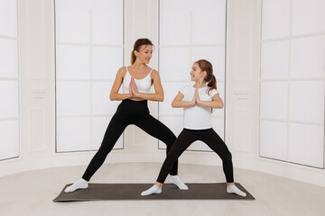 Obraz premium Young mother with little daughter practicing yoga and doing asana