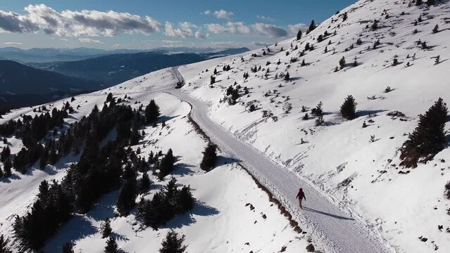 Aerial view of a person walking on a snow covered road, on the italian Alp mountains, in winter
