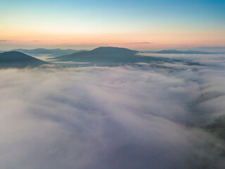 The rays of dawn over the fog in the Ukrainian Carpathians. Aerial drone view.