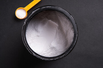 Sports creatine in a container on a black background close-up view from above