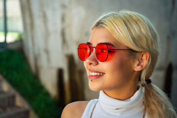 Close-up of a beautiful young smiling Latina woman wearing a white t-shirt and red sunglasses.