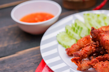 Fried Pork Belly with Fish Sauce and Sticky Rice Served on a white plate on a black wooden floor.