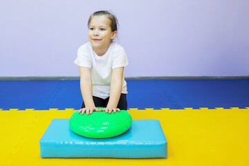 a little girl plays with a studded ball in a children's center and massages her hands