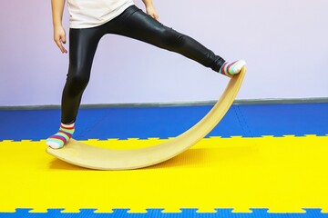 a little girl in white swings on a special balance beam to the sides in a children's center so as...
