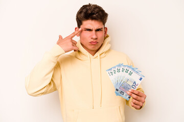 Young caucasian man holding banknotes isolated on white background showing a disappointment gesture with forefinger.