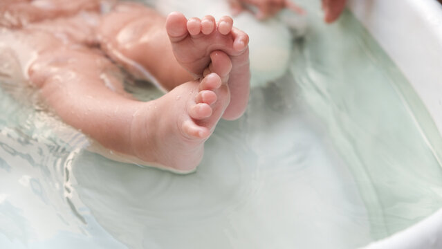 Baby Feet In The Bathroom With White Water Close-up. Happy Kids, 3 Months Feet.