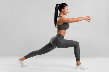 Fitness woman doing lunges exercises for leg muscle training. Active girl doing front forward one...