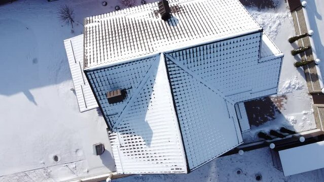 a brick house stands in winter under the snow on a bright frosty day