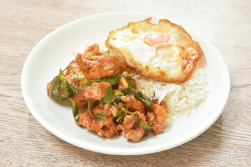 spicy fried slice pork in curry with topping crispy egg on rice in plate