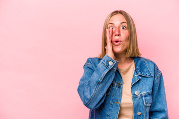 Young caucasian woman isolated on pink background is saying a secret hot braking news and looking aside