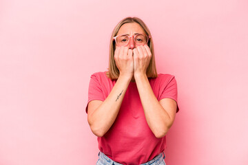 Young caucasian woman isolated on pink background biting fingernails, nervous and very anxious.