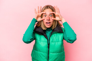 Young caucasian woman isolated on pink background keeping eyes opened to find a success opportunity.