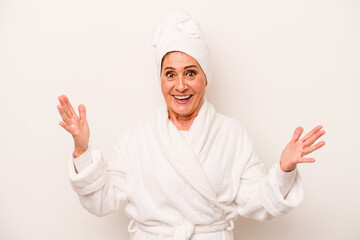 Middle age caucasian woman wearing a bathrobe isolated on white background receiving a pleasant surprise, excited and raising hands.