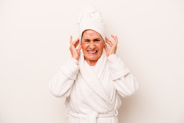 Middle age caucasian woman wearing a bathrobe isolated on white background covering ears with hands.