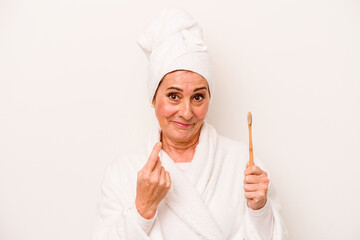 Middle age caucasian woman wearing a bathrobe holding toothbrush isolated on white background pointing with finger at you as if inviting come closer.