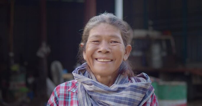 The happy smile of a partially white-haired Asian farmer and a worker in the farm at the rural area, who is a poor person and had to work hard all day in the fields.