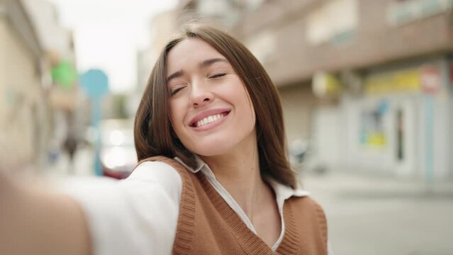 Young hispanic woman smiling confident making selfie by the camera at street