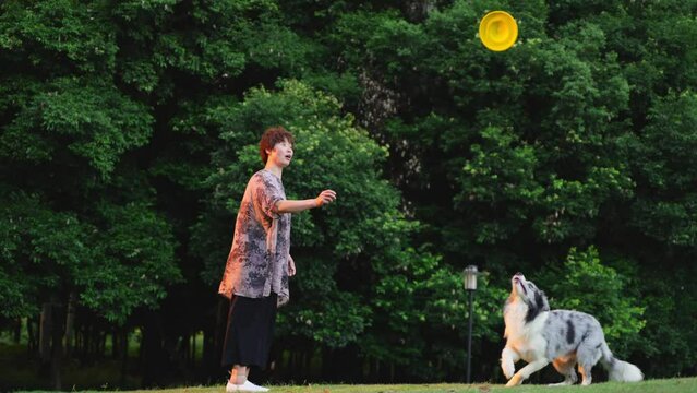 Middle aged Asian woman playing frisbee with a lovely dog