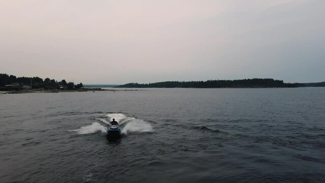 Guys riding jet skis on blue water in Sweden. Drone flying over jet skis