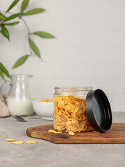 Fototapeta na wymiar Plastic or glass container with cornflakes for breakfast. Vertical frame on a light background.